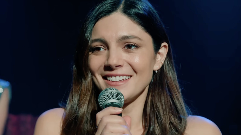 Monica Barbaro as Allie holding a microphone in One Night Only