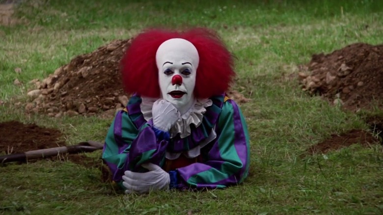 Pennywise in a field half underground in It