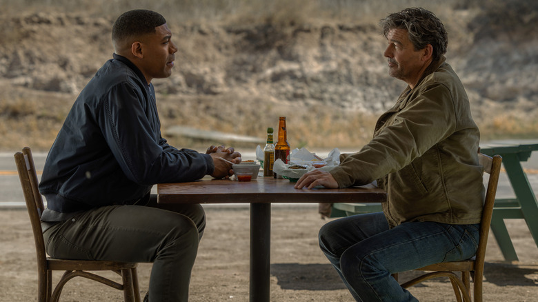 Aaron Pierre as John Stewart sitting at a roadside restaurant table opposite Kyle Chandler as Hal Jordan in Lanterns