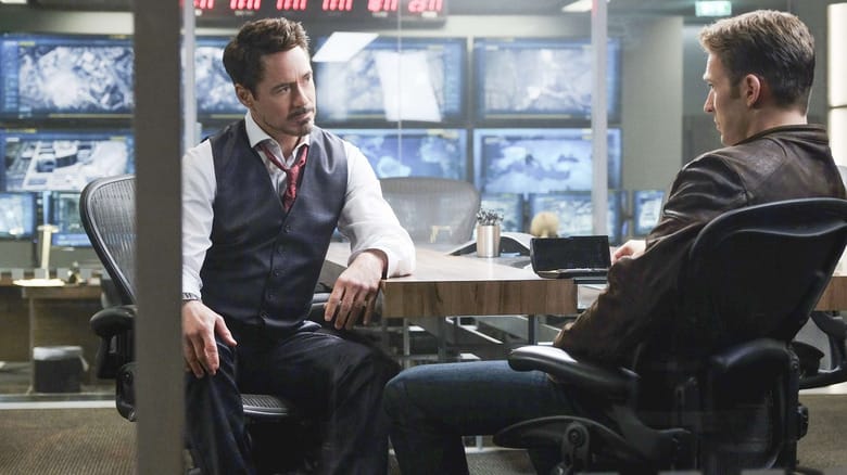 Robert Downey Jr. as Tony Stark sitting at a table in a conference room opposite Chris Evans as Steve Rogers in Captain America: Civil War