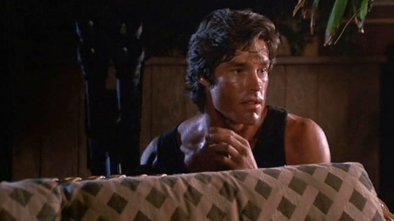 Ronn Moss as Roddy Abilene crouched behind a couch in Hard Ticket to Hawaii
