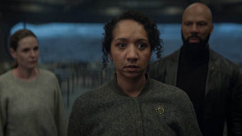 Alexandria Riley as Camille Sims standing next to Rebecca Ferguson as Juliette Nichols and Common as Robert Sims in a cafeteria in Silo