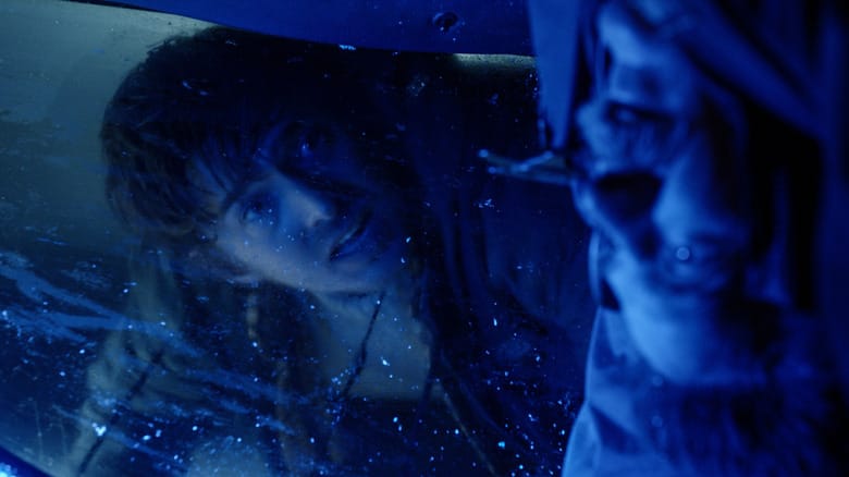 Austin Abrams as Bryan looking through the window of a car at a dead body hanging upside down in Resident Evil