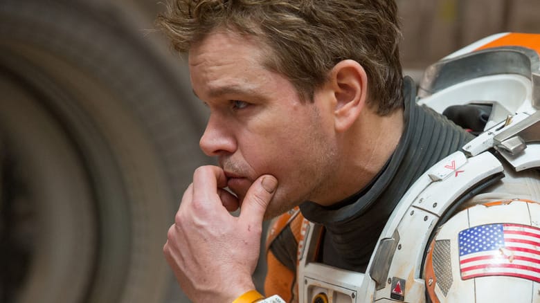 Matt Damon as Mark Watney sitting in a thoughtful pose in The Martian