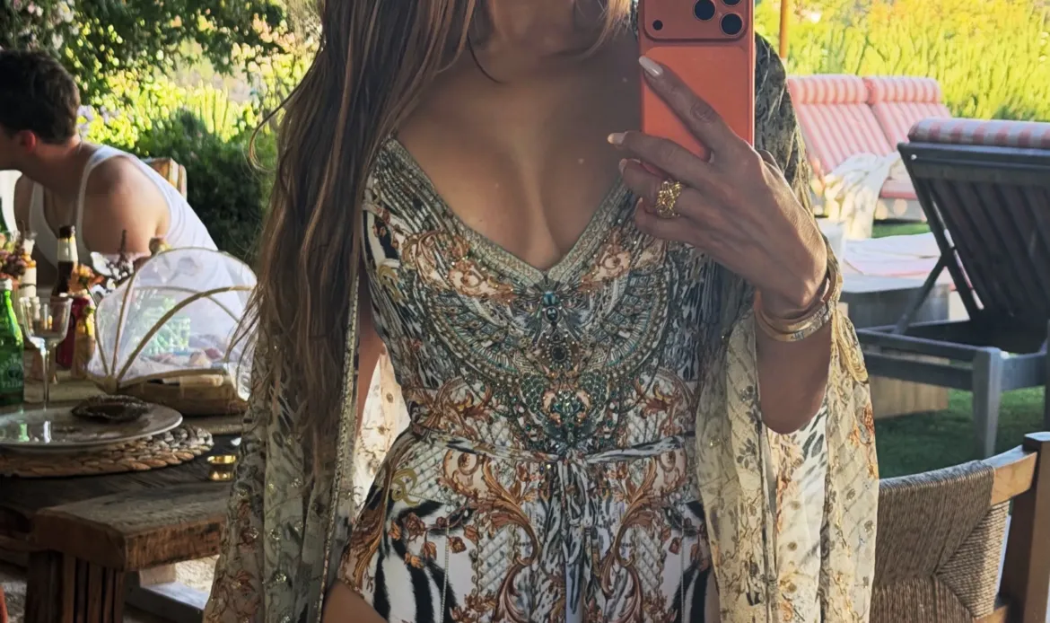 Jennifer Lopez takes a mirror selfie outdoors wearing a printed swimsuit and robe.