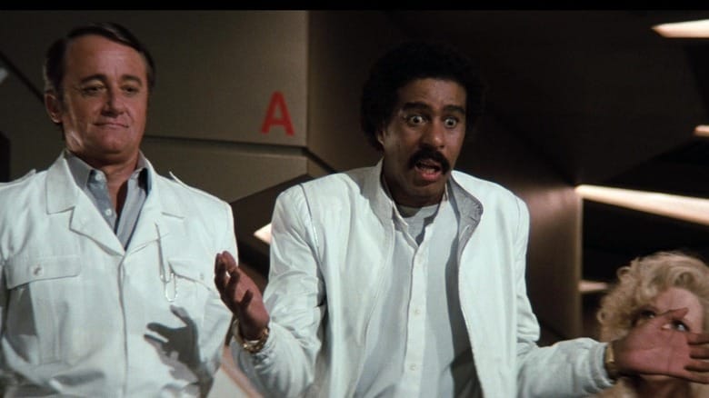 Robert Vaughn's Ross Webster stands beside Richard Pryor as Gus Gorman and Pamela Stephenson's Lorelei Ambrosia in Superman III