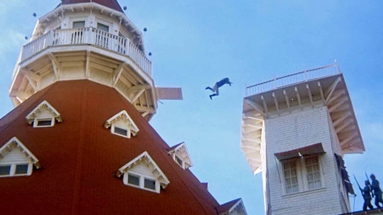 Steve Railsback as Cameron leaps from the roof of a house. to another roof in The Stunt Man