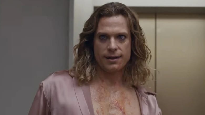 Sam Reid as Lestat de Lioncourt in The Vampire Lestat, wearing a silk robe open and barely showing his fangs.