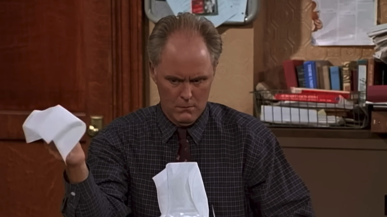 John Lithgow's Dick Solomon looks confused as he pulls tissues out of a box in 3rd Rock from the Sun