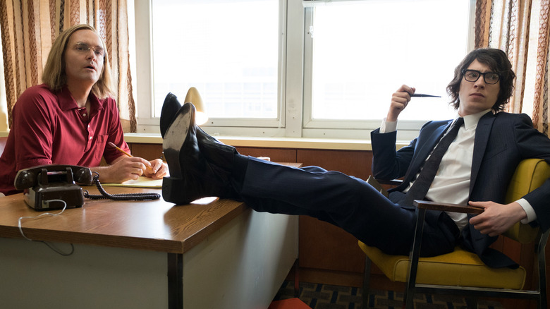 Will Forte as Doug Kenney and Domhnall Gleeson as Henry Beard sitting at his desk in A Futile and Stupid Gesture