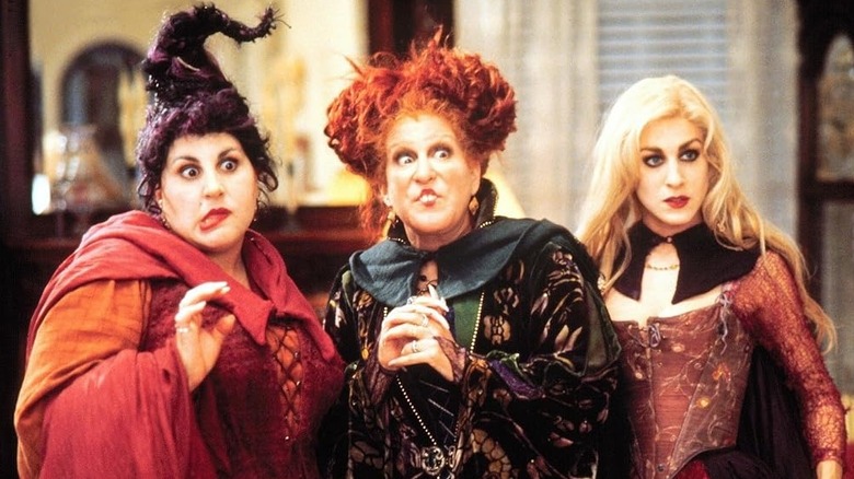 Kathy Najimy as Mary Sanderson, Bette Midler as Winifred Sanderson, and Sarah Jessica Parker as Sarah Sanderson standing next to one another in Hocus Pocus
