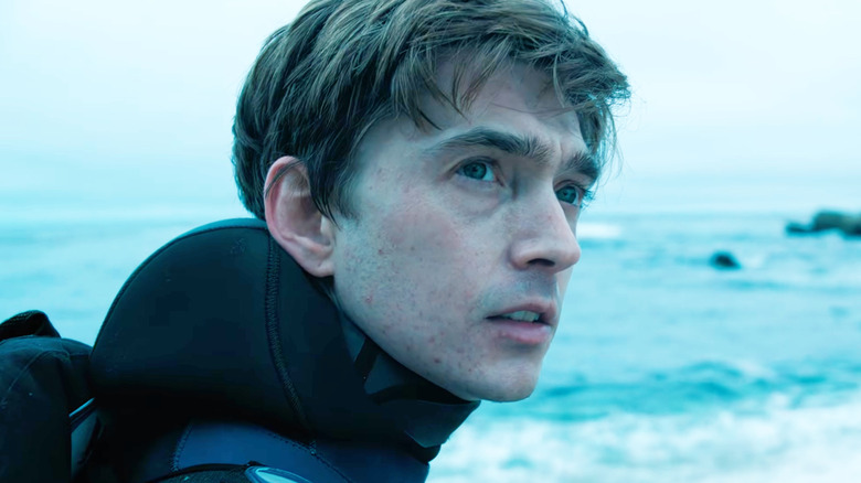 Austin Abrams as Jay Gardiner wearing scuba gear and standing on the beach in Whalefall