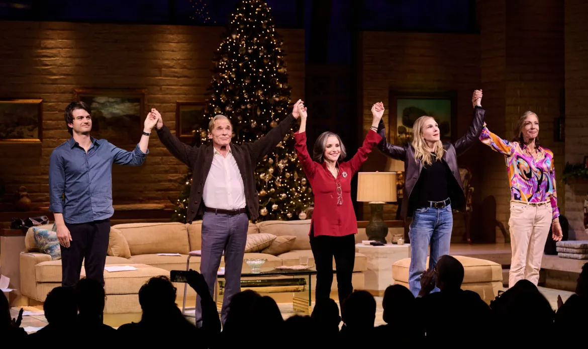 Joe Keery, Ed Harris, Julia Louis-Dreyfus, Lily Rabe, and Allison Janney take a bow on stage, holding hands in a line with a Christmas tree in the background.