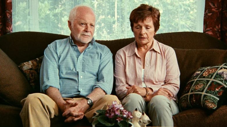 Garrett Long (Robin Cuming) and Iris Long (Judith Roberts) sit forlornly on a couch in Lake Mungo