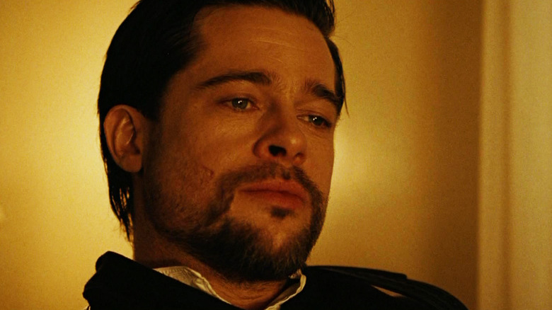 Brad Pitt's Jesse James looks down as he sits in a warmly lit room in The Assassination of Jesse James by the Coward Robert Ford.jpg