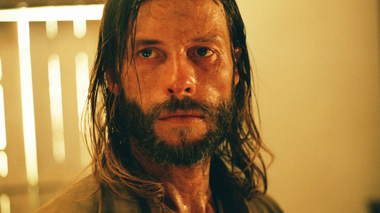 A medium shot of Guy Pearce as Charlie Burns in The Proposition, with shoulder-length hair and looking sweaty and dirty.