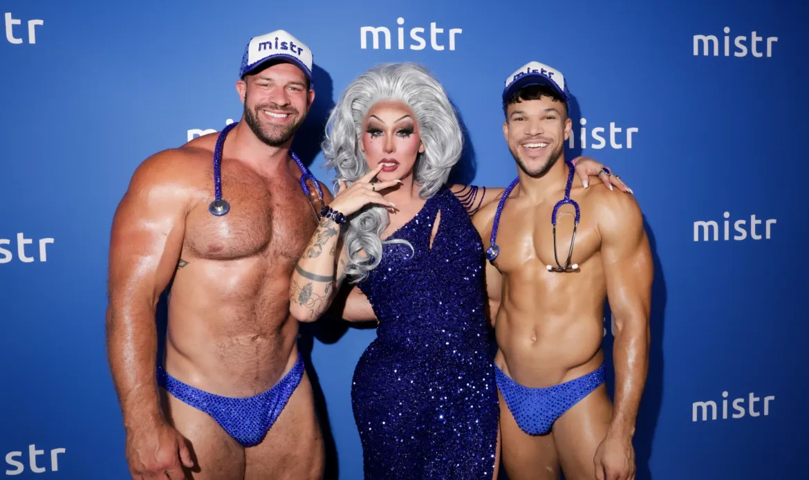 Salina Estitties poses with two shirtless men wearing blue underwear, baseball caps, and stethoscopes at MISTR's 2nd Annual National PrEP Day Celebration.