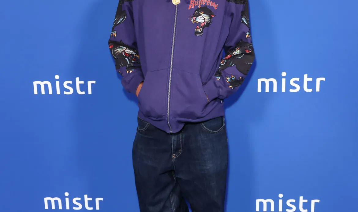 Omar Apollo poses on a blue carpet in front of a step-and-repeat backdrop featuring the MISTR logo.