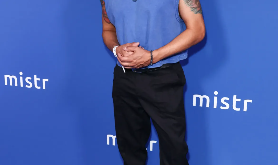  Jai Rodriguez poses in a blue sleeveless top and black pants in front of a blue step-and-repeat backdrop at MISTR's 2nd Annual National PrEP Day Celebration.